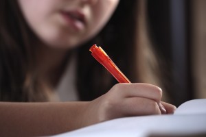 Young girl writing whilst studying or doing homework